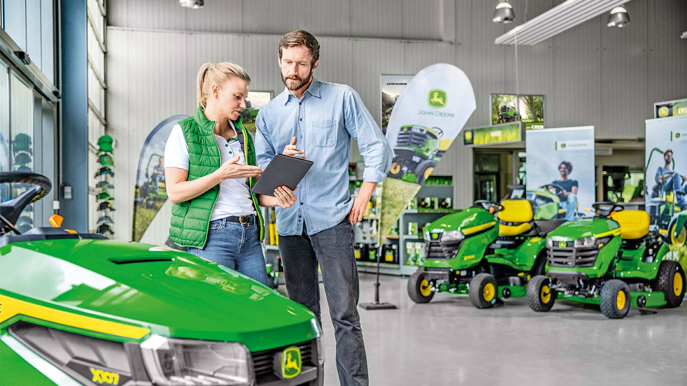 Dealer John Deere doradza klientowi w sprawie zakupu kosiarki John Deere.