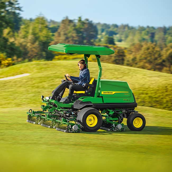 Konserwator pól golfowych pracuje na terenie zielonym z kosiarką do fairway John Deere